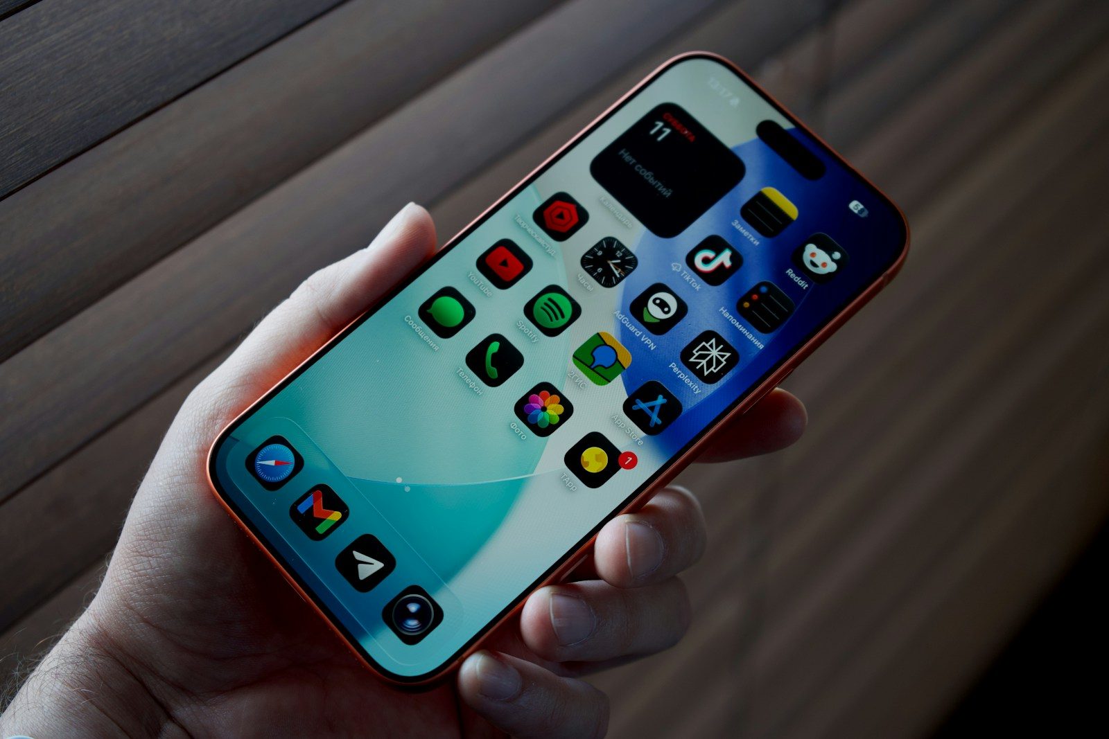 Hand holding a smartphone with colorful app icons.